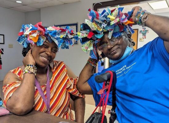 Two older adult participants show their handmade head pieces.