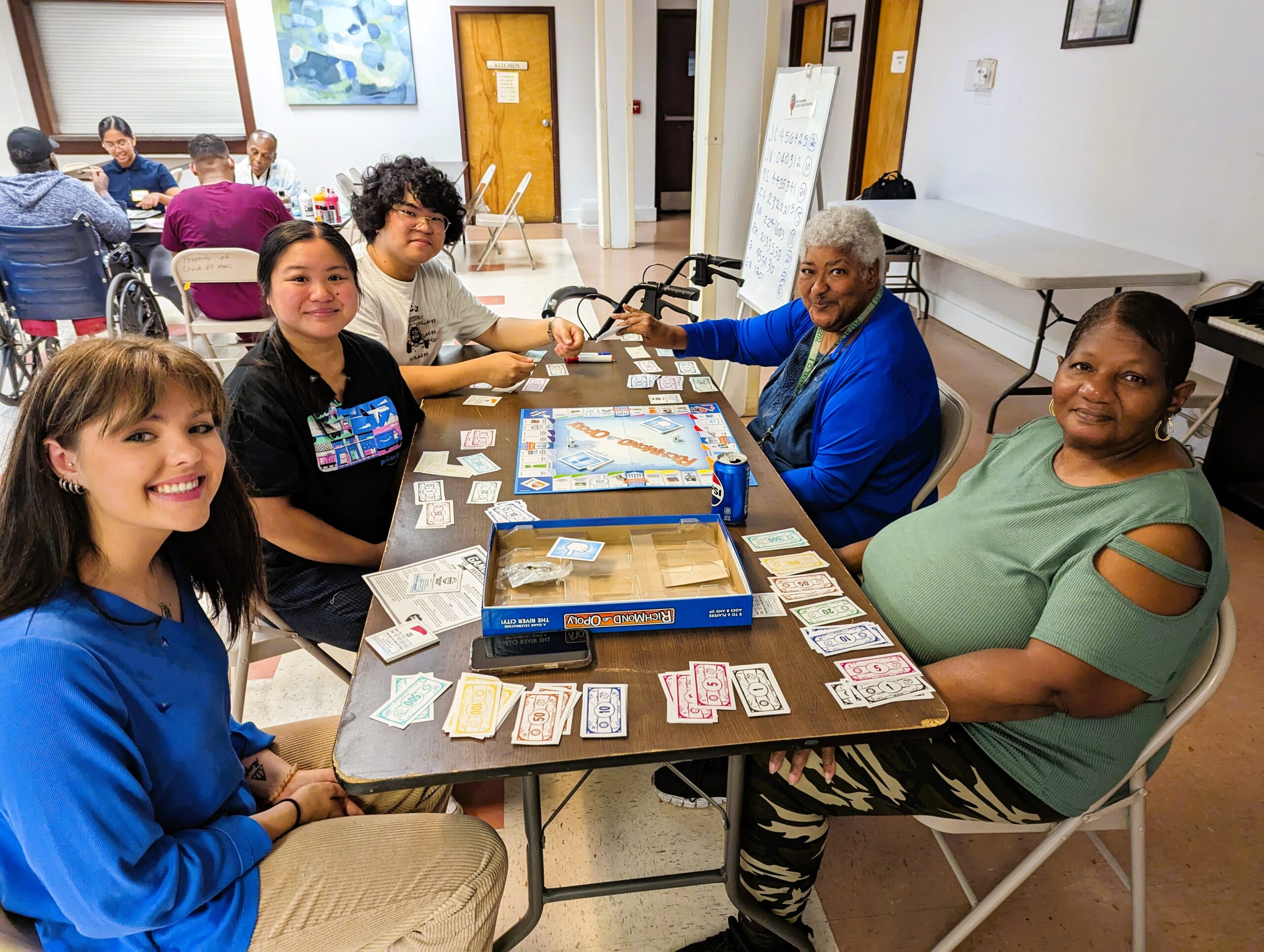 Volunteers and older adult participants play board game.
