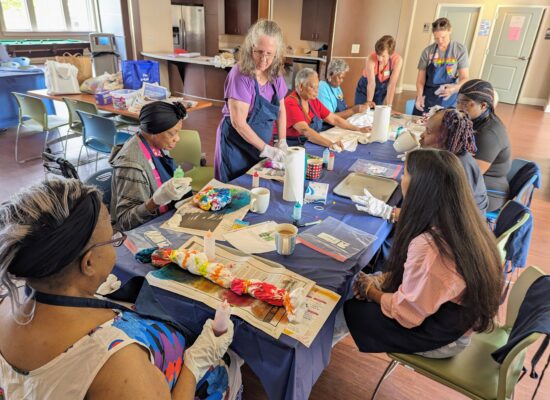 Volunteers and older adult participants do tie dye activity with shirts.