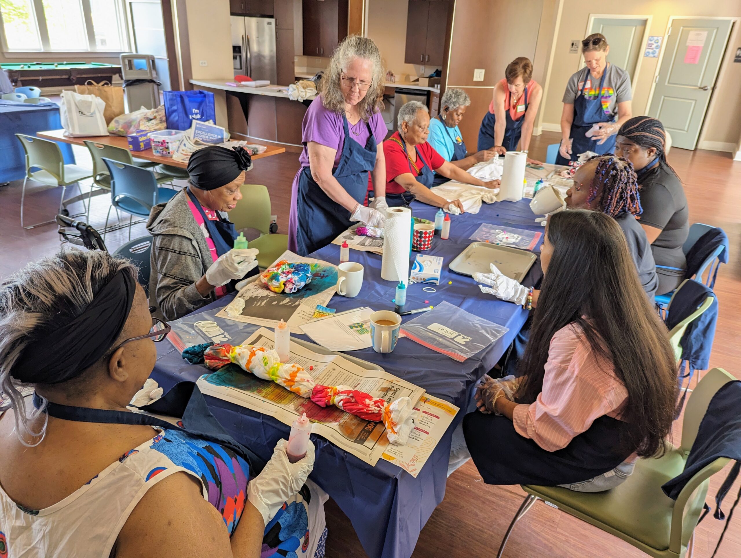 Volunteers and older adult participants do tie dye activity with shirts.