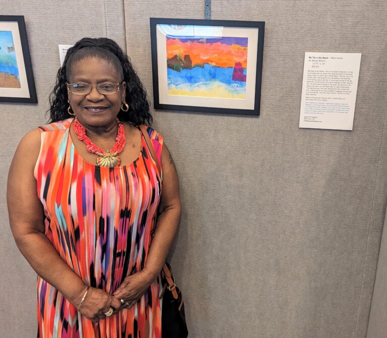 Lady posing next to her art piece.