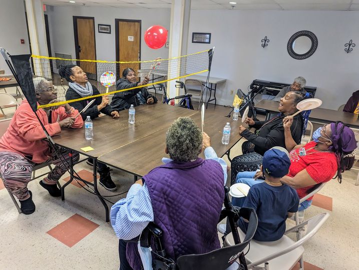 Older adult participants play pickleball with balloon.