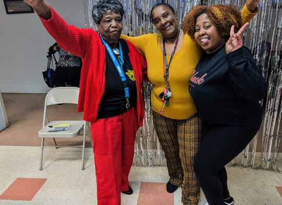 Volunteer and two older adult participants pose with peace signs.