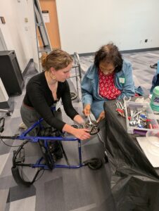 Trainer assisting an older adult participant on repairing a rollator.