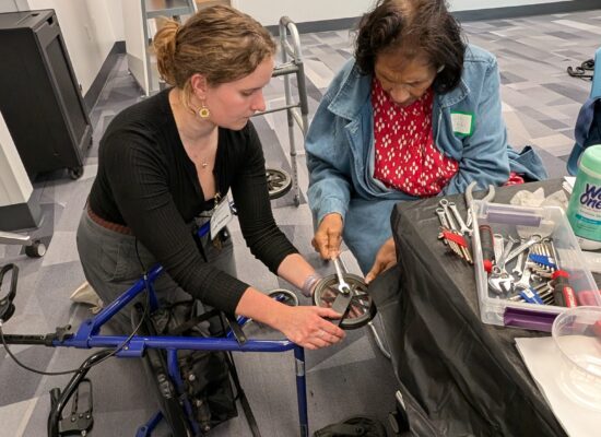 Trainer assisting an older adult participant on repairing a rollator.