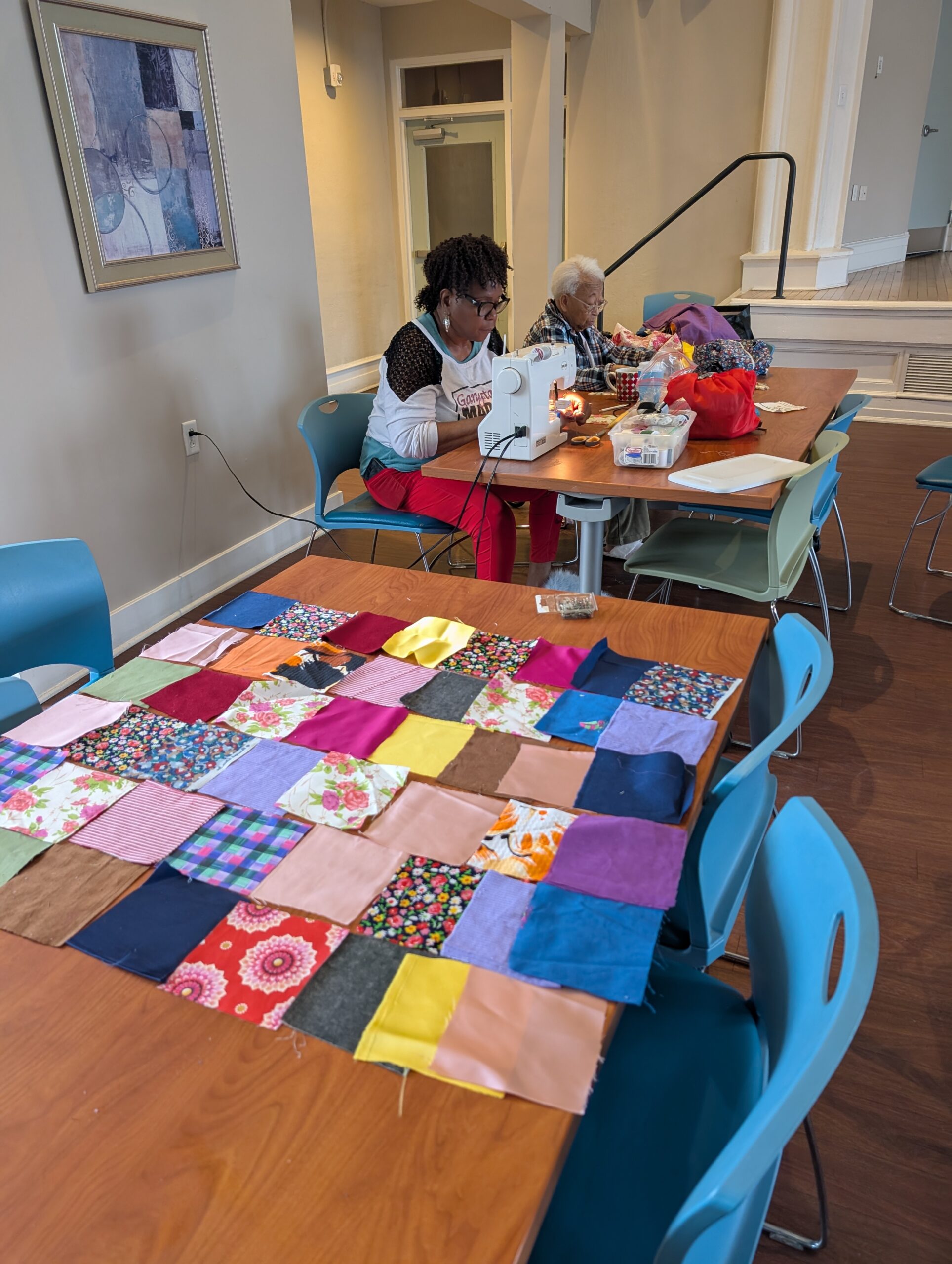 Participant using sewing machine to connect fabric squares to make a quilt.