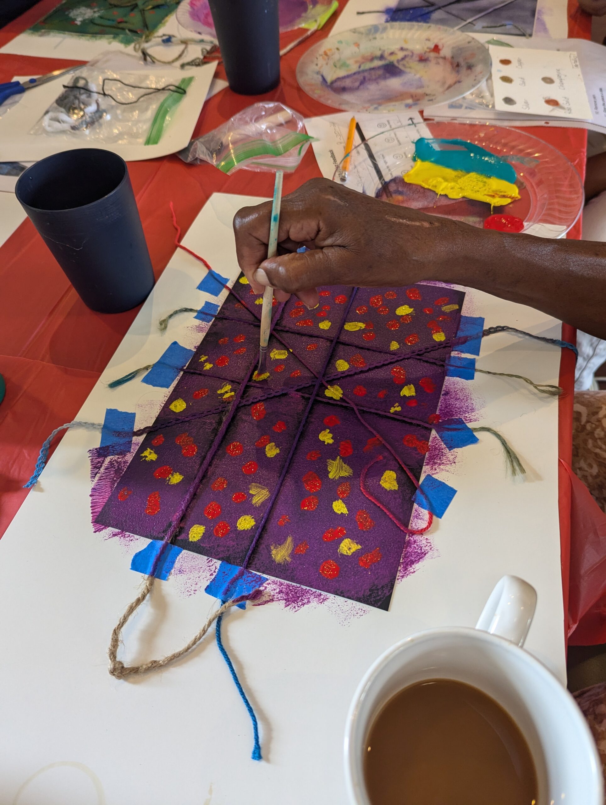 Yarn being used to create lines on artwork as participant paints over it.