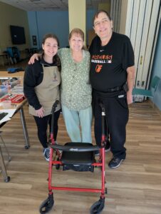 Volunteer poses with a couple and their repaired rollator.