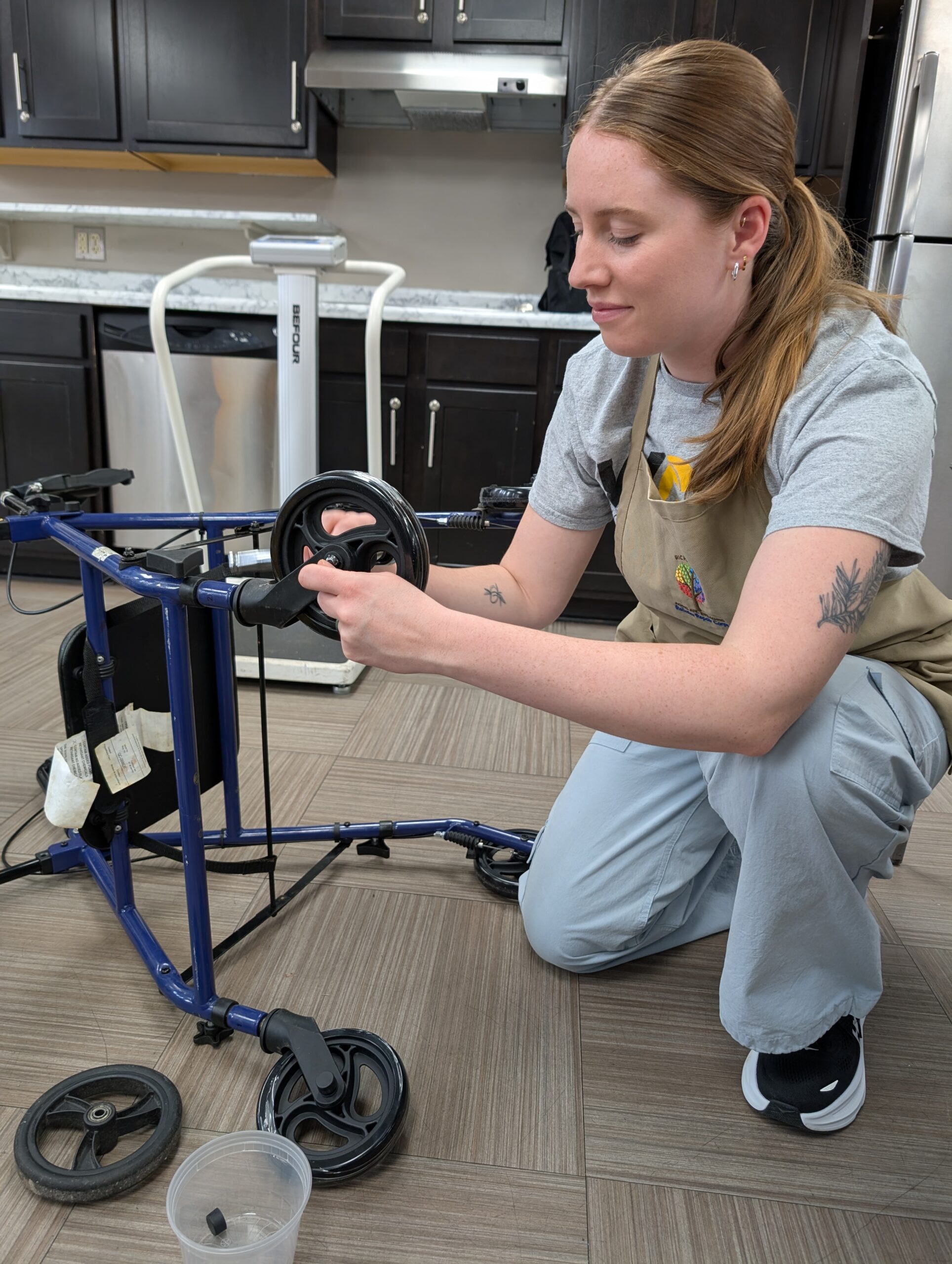 Volunteer fixes a wheel on a broken rollator.